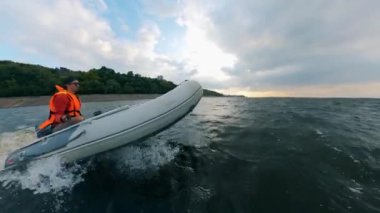 Adam dalgalar ile nehir üzerinde bir motorbot sürmek.