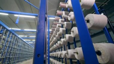 Bir tekstil fabrikasında sıra sırahalinde raflara yerleştirilen beyaz iplikli clews. Tekstil endüstrisi konsepti.