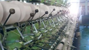 Metal makineleri bir tekstil fabrikasında ipliklerle çalışır, bobinlere.