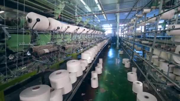 A facility with working machines, spooling threads onto bobbins. Weaving machine working at textile fabric. — Stock Video