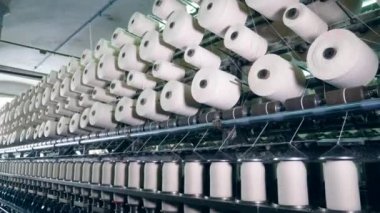 Dokuma makinesi tekstil kumaş ta çalışır. Modern bir tesiste beyaz iplikli iplik bobinleri.