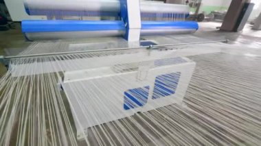Bir tekstil fabrikasında özel bir dokuma tezgahında dokunan beyaz kumaş.