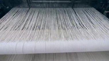 Dokumatezgah bir tekstil fabrikasında beyaz kumaş ile çalışır. Tekstil fabrikası ekipmanları iş yerinde.