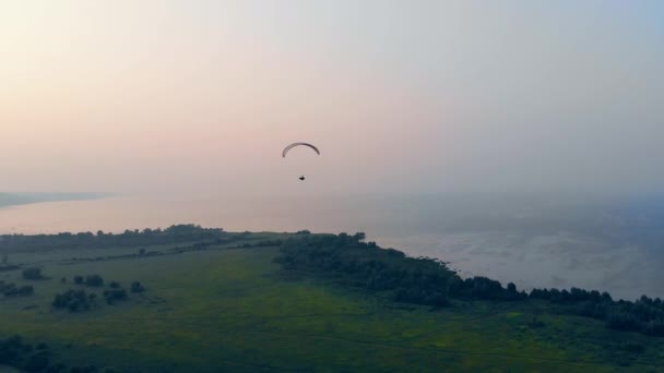 Une personne survolant un grand champ avec un parapente. Parapente dans le ciel . — Video