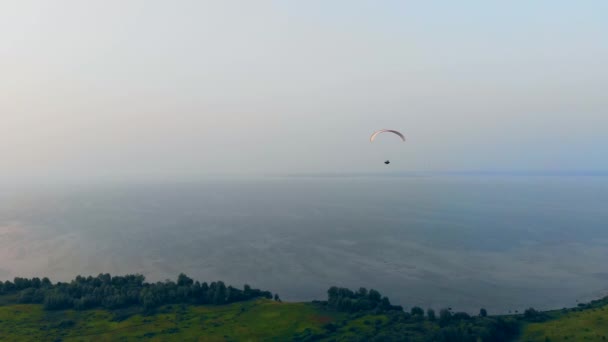 Um atleta voando com um parapente sobre um campo. Parapente no céu . — Vídeo de Stock