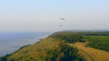 Adam, tarlaların üzerinde büyük bir yamaç paraşütü yle yola çıktı. Gökyüzünde yamaç paraşütü.