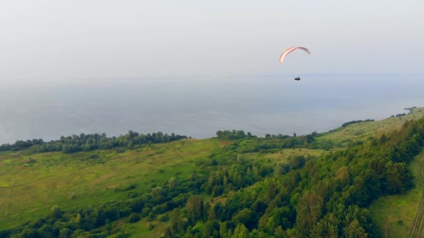 Man paragliding over groen veld. — Stockvideo
