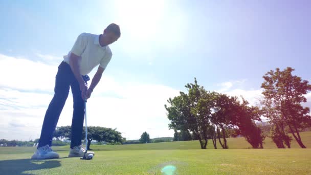 Golf speler zet een bal in een gat. — Stockvideo