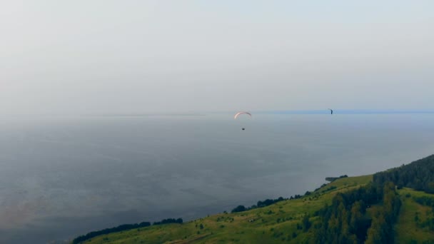 Человек, летящий с парапланеристом над зеленым холмом. Параплан в небе . — стоковое видео