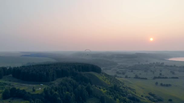 Muž pluje s kluzák při západu slunce na obloze. Paragliding, akce, extrémní sportovní koncepce. — Stock video