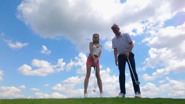 Entrenamiento de hombre y mujer, jugar al golf en un campo . — Vídeos de Stock