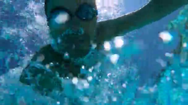 Un hombre nada bajo el agua en una piscina, en cámara lenta . — Vídeos de Stock