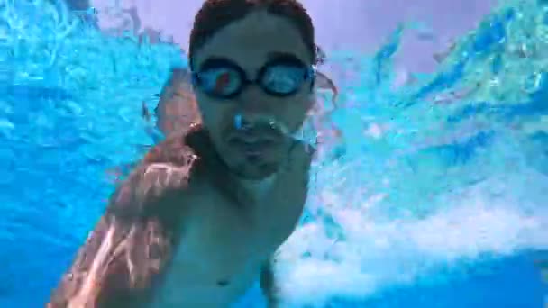 Una persona nada en una piscina, con gafas, cámara lenta . — Vídeos de Stock