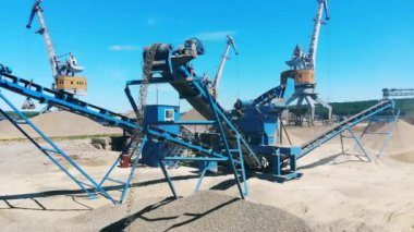 Bir taş ocağında çalışan vinçler ve kırıcı, moloz madenciliği. Madencilik endüstrisi ekipmanları.