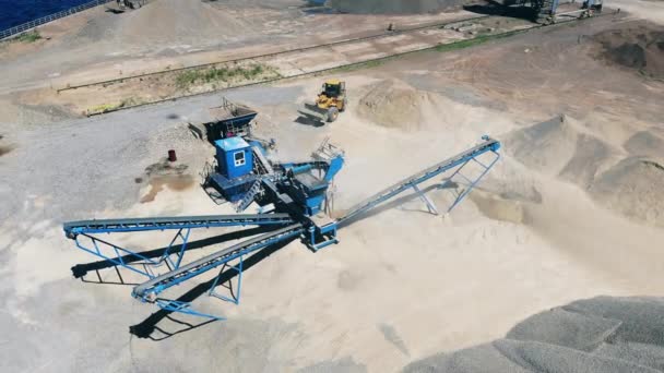 Tracteur jaune travaille sur un site minier, décombres en mouvement. Machine de concassage de pierres dans une carrière minière . — Video