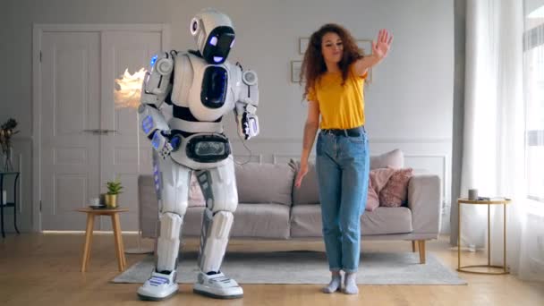 Die schöne Dame und der Roboter tanzen im Wohnzimmer. Smart Home Konzept. — Stockvideo