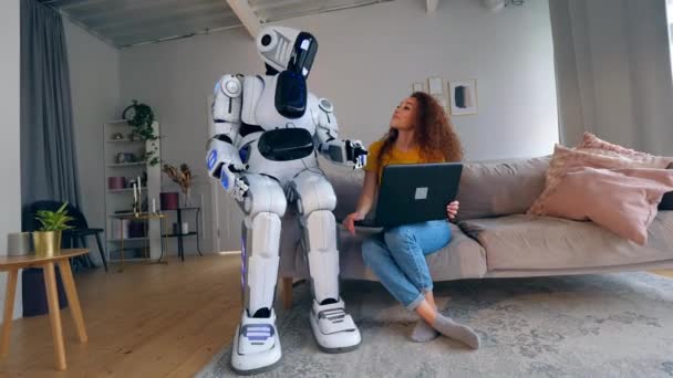 Mladá žena pracuje na přenosném počítači a mluví s robotem. Robot, lidský, podobný kyber. — Stock video