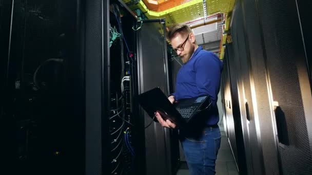 IT technician is analyzing a server on his laptop — Stock Video