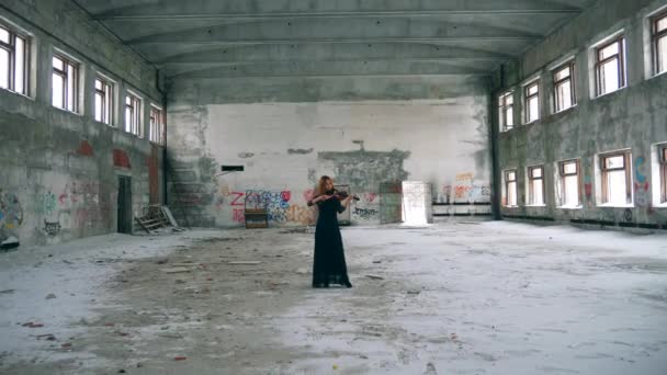 Edificio abandonado y una mujer tocando el violín en él — Vídeo de stock