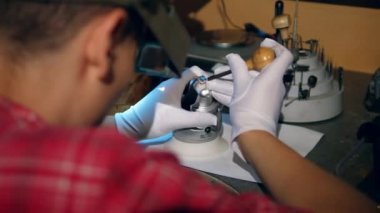 Bir kuyumcu bir atölyede bir yüzük ile çalışır.