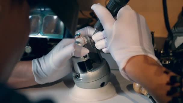 Professionele juwelier graveert een gouden ring met een gereedschap. — Stockvideo