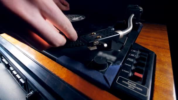 Een persoon plaatst een vinyl schijf op een muziekspeler en start het. — Stockvideo