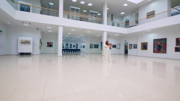 Galeriesaal mit einer Frau im Kleid, die Geige spielt — Stockvideo