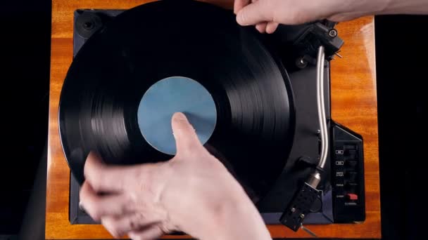 Person turns on a musical player, placing a needle on a vinyl record. — Stock Video