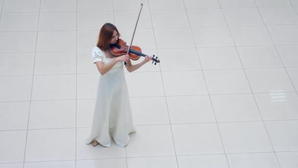 白色地板，一位女士站在地板上，拉小提琴 — 图库视频影像