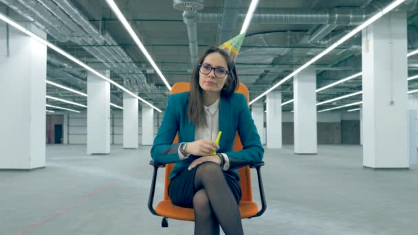 Concept de fête ennuyeux. Triste femme manager dans un chapeau d'anniversaire est assis dans une chaise roulante — Video