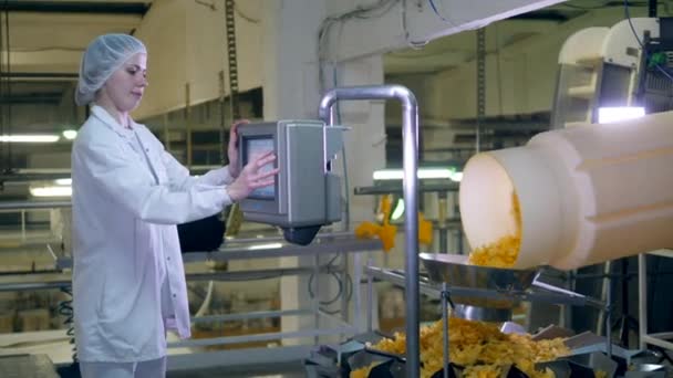 Kobieta pracuje z maszyną fabryczną, kontrolując Przenośnik z frytkami. — Wideo stockowe