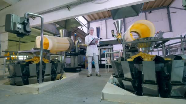 Una mujer trabaja en una fábrica de alimentos, comprobando el proceso de clasificación de chips . — Vídeo de stock