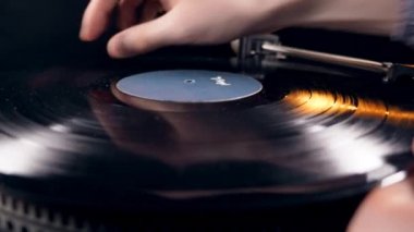 Kişi bir oyuncu ya da bir vinil kayıt koyar ve açar.