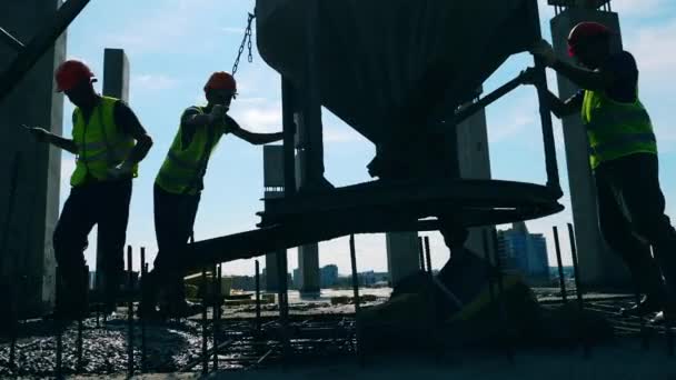 Рабочие наливают бетон из канистры — стоковое видео