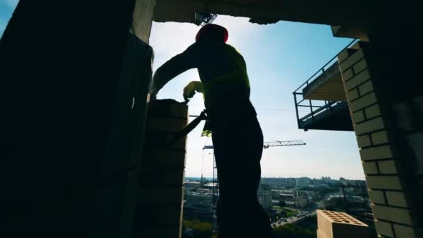 Construtor retroiluminado está espalhando concreto nos tijolos — Vídeo de Stock