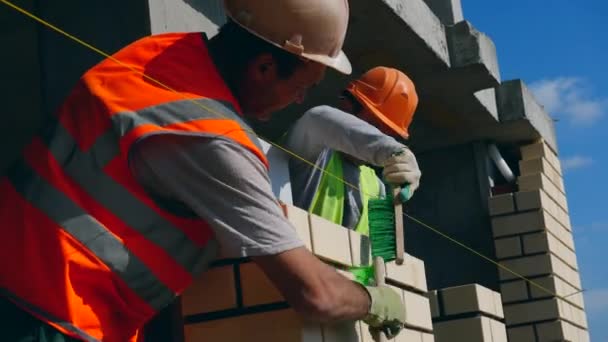 Männliche Arbeiter putzen eine neu errichtete Ziegelmauer — Stockvideo