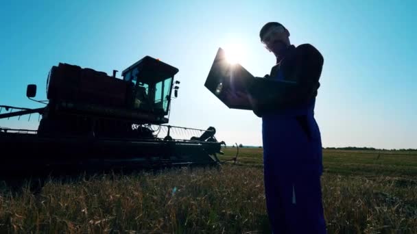 Agrónomo se encuentra en un campo, trabajando con un ordenador portátil . — Vídeo de stock