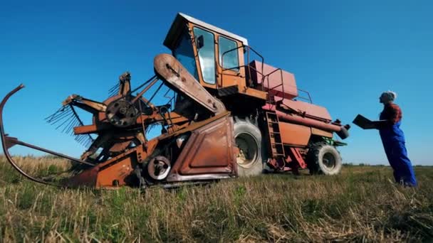 Человек проверяет трактор, стоя на поле. . — стоковое видео