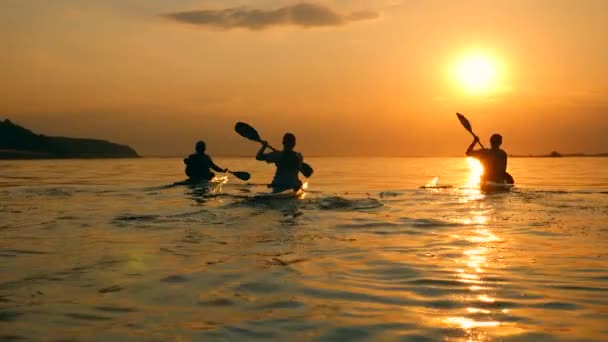 O sol está se pondo e as pessoas estão navegando em canoas — Vídeo de Stock