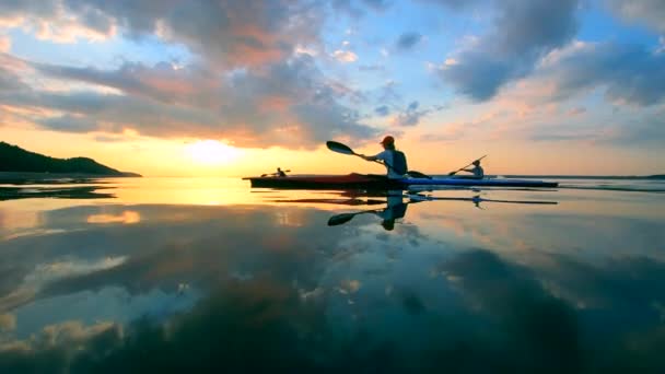 人々がカヌーで横切る夕日の湖 — ストック動画