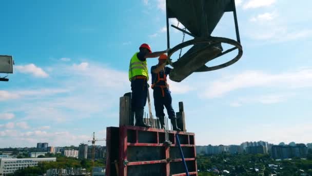 Os trabalhadores estão em pé no bloco de construção com uma cisterna de cimento — Vídeo de Stock