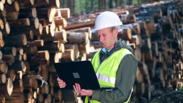 Männlicher Arbeiter tippt auf Laptop, während er Koffer kontrolliert. — Stockvideo