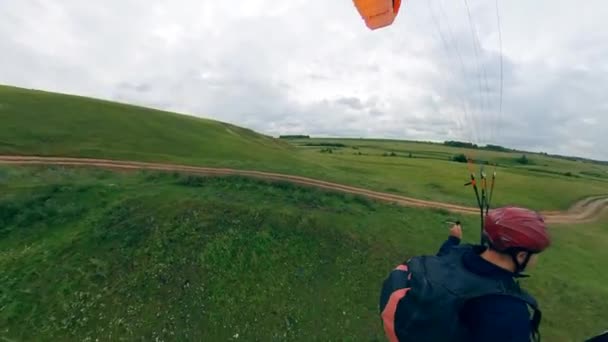 Vista de uma pessoa, voando com um parapente sobre campos verdes . — Vídeo de Stock