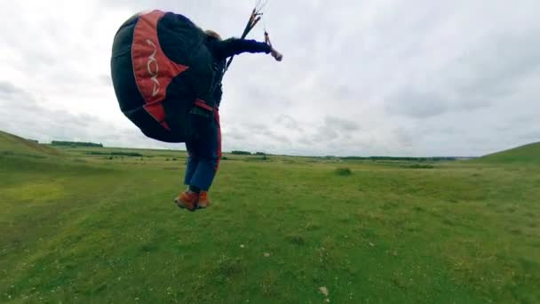 Sportman vliegen een Paraglider, landt op een veld. — Stockvideo