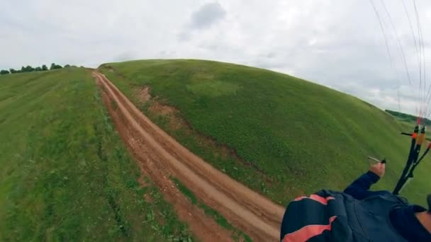 Mann mit Helm fliegt mit Segelflugzeug über grüne Wiese. — Stockvideo