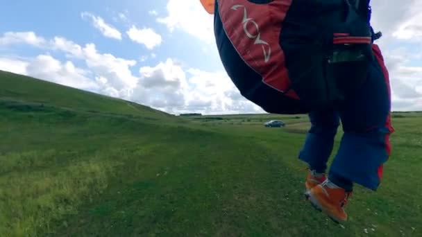 Um homem entra em terra depois de voar com um parapente . — Vídeo de Stock