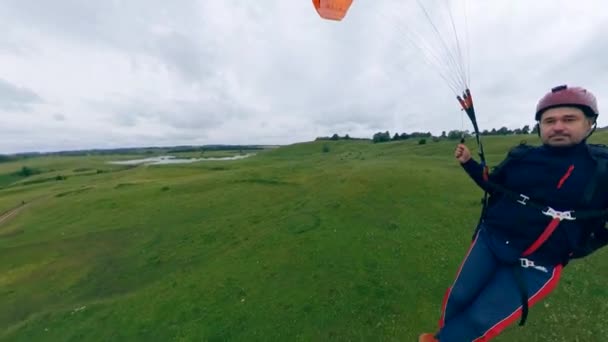 Atleta macho voa um planador laranja sobre o campo . — Vídeo de Stock