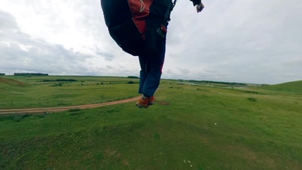 Egy sportoló repül egy vitorlázó, leszállás egy zöld mező. — Stock videók