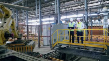 Fabrika işçileri modern robotik kol çalışmasını yönetiyor