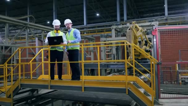 Dos especialistas masculinos hablando cerca de equipos industriales modernos . — Vídeos de Stock